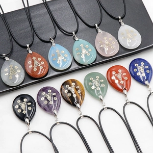 Détail des pendentifs en pierre naturelle goutte d'eau avec symboles de yoga chakra