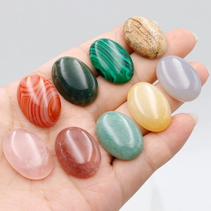 Hand holding nine pieces of mixed 18x25mm oval natural gemstones for DIY jewelry craft