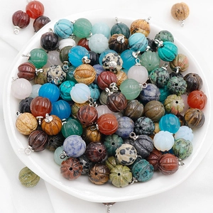 Natural gemstone pumpkin pendants in quartz and agate with silver metal loops on a plate