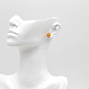 Minimalistischer Achat-Ohrstecker mit polierter orangefarbener Perle auf weißer Büste