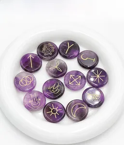 Close-up of 13 purple amethyst rune stones with gold engraved mystical symbols on a plate