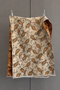 Détail du tissage jacquard avec motif paisley et franges sur l'écharpe beige