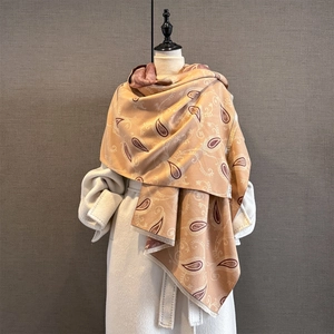Détail d'un châle pashmina à motif paisley avec franges sur un manteau blanc chic