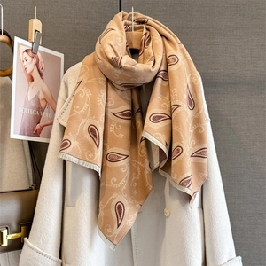 Châle cachemire beige à motifs paisley avec franges sur un manteau blanc pour l'hiver