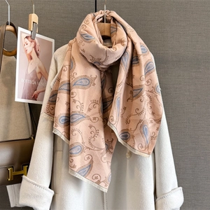 Écharpe en cachemire rose à motif paisley avec franges sur un manteau blanc