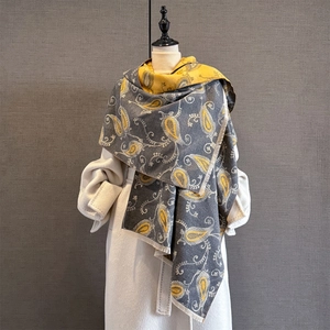 Détail d'écharpe en cachemire paisley jaune et gris avec franges sur manteau blanc