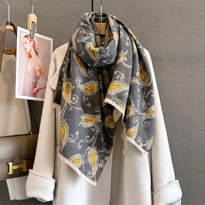 Vue détaillée d'une écharpe cachemire à motif paisley gris sur un manteau en laine