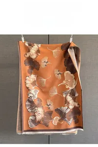 Vue détaillée du motif jacquard feuilles de ginkgo orange et marron sur une écharpe