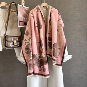 Détail de l'écharpe en cachemire rose et marron avec feuilles de ginkgo et franges sur manteau