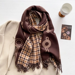 Detail of a brown and beige cashmere-like scarf with houndstooth pattern and soft fringes