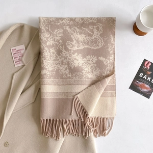 Macro detail of nude cashmere-style scarf featuring jacquard floral patterns and fringe