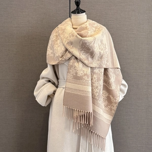 Detail of beige floral jacquard shawl with tassel fringe on a white coat