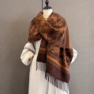 Detailed view of vintage patterned shawl with fringe trim on an elegant white coat