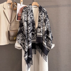 Detail of a thick black and white floral pattern shawl with tassels in a workspace setting