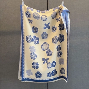 Vue détaillée des bords à franges douces et des motifs floraux bleus sur ce châle élégant