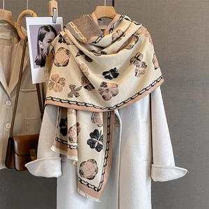 Écharpe cachemire à motif floral et nœud portée avec un manteau blanc élégant