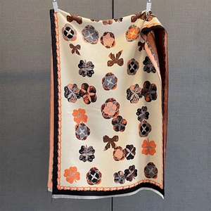 Gros plan sur l'imprimé floral du châle en maille épaisse beige avec franges