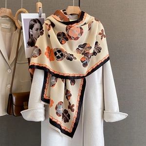 Écharpe élégante à imprimé floral avec glands drapée sur un manteau blanc
