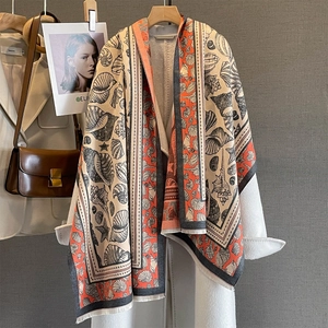 Warm beige autumn shawl with orange shell prints and fine fringe on a white coat