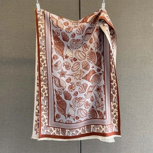 Detailed close-up of seashell print scarf featuring marine motifs and delicate white tassels