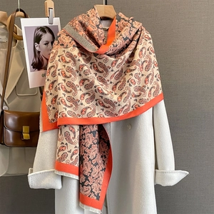 Écharpe cachemire à motif cachemire orange et gris avec franges sur un manteau blanc