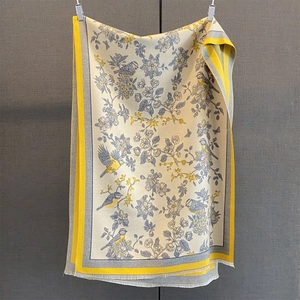 Close-up of bird print scarf with contrast yellow borders and fine tassel details