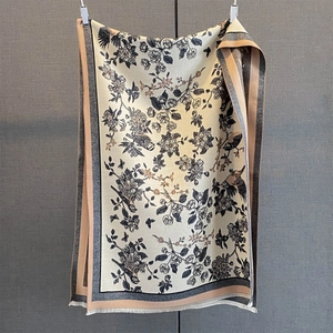 Detail of floral and bird print scarf with color-block edges and delicate tassels