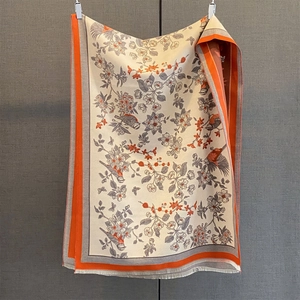 Detail of floral bird print scarf with orange borders and tassel fringe texture