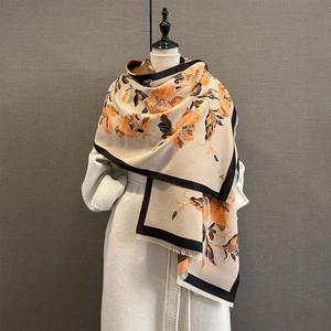 Détail d'un châle jacquard floral sur manteau blanc avec fleurs oranges et franges