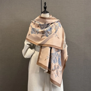 Détail du motif floral jacquard et des franges douces sur l'écharpe beige