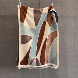 Detail of geometric pattern cashmere-like scarf showing soft texture and tassel edges