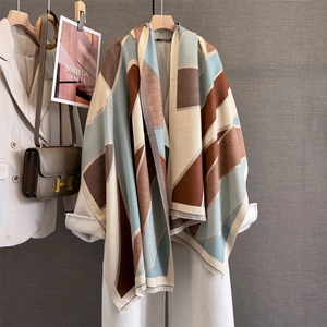 Detailed view of the geometric color-block scarf with fringes on a white coat