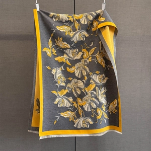 Détail du châle d'hiver gris avec motifs floraux jaunes et finitions à franges blanches