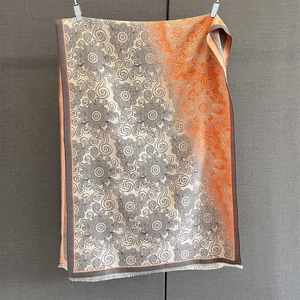 Close-up of jacquard floral pattern and fine tassel fringe on orange cashmere-feel scarf
