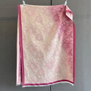 Detail of pink and beige floral paisley patterns with white fringes on a soft shawl scarf