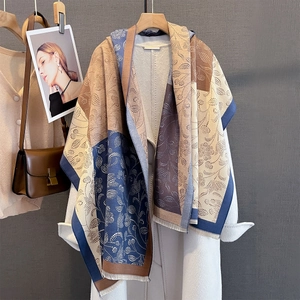 Detail of cashmere-feel scarf featuring navy and caramel geometric patterns on a white coat