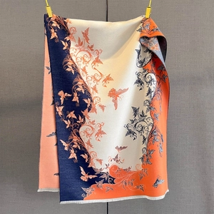 Dettaglio di motivi jacquard floreali e farfalle con frange su una morbida sciarpa in cashmere