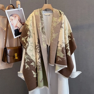 Dettaglio scialle effetto cashmere con motivo floreale e nappe su un cappotto bianco