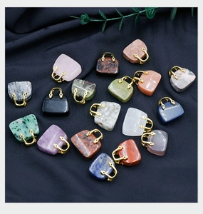 Detailed view of mini natural stone handbag pendants with golden handles on blue silk