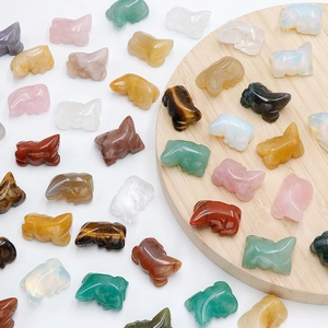 Assorted natural crystal frog carvings in rose quartz, jade, and tiger eye on wood