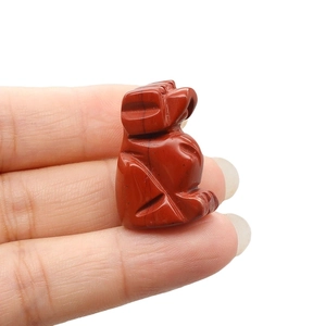 Red jasper hand-carved animal figurine with natural stone texture on white background