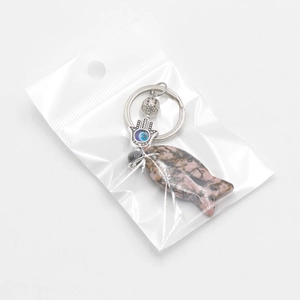 Pink stone fish keychain with Evil Eye Hamsa charm on white background in packaging