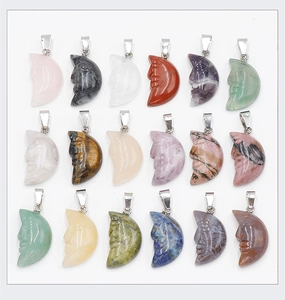 Flat lay of 18 diverse natural crystal crescent moon pendants with carved faces and silver bails