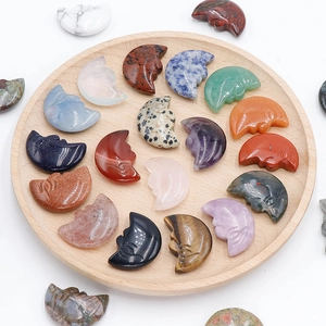 Carved natural crystal crescent moon face pendants in assorted gemstones on wood tray