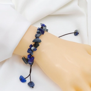 Naturstein-Armband aus Lapislazuli mit verstellbarer Kordel an einer Hand auf weißem Stoff