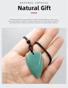 Detailed view of hand-held heart-shaped green quartz stone necklace with black woven cord