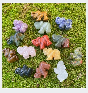 Vista detallada de minifiguritas de elefantes en cristal natural sobre musgo verde