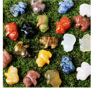 Miniature hand-carved natural crystal pigs in various gemstones on green moss
