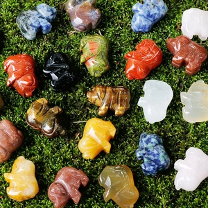 Mini carved crystal pig figurines made of natural tiger eye and quartz on green moss