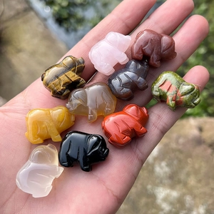 Variety of 1-inch carved natural crystal and agate pig figurines held in hand
